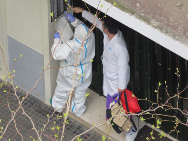 Dos sanitarios en un portal visitan a un enfermo de coronavirus