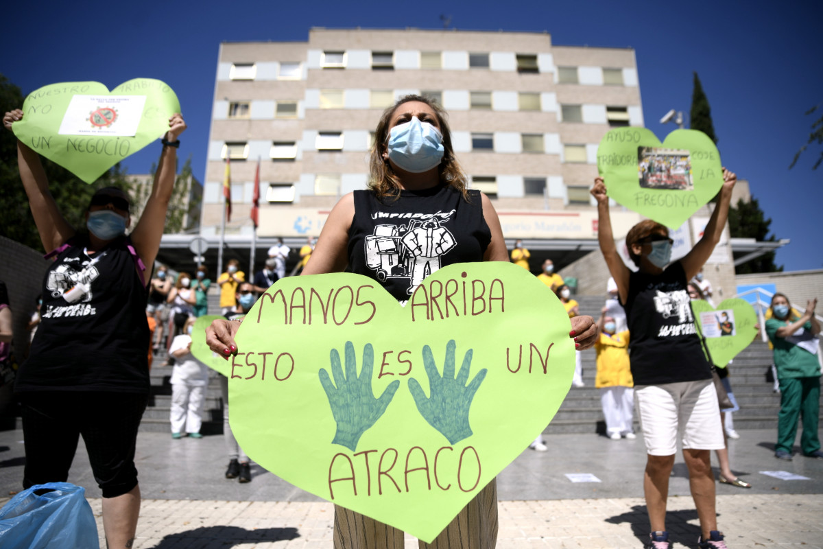 Una trabajadora de limpieza del Hospital Gregorio Marañón sujeta un corazón verde -que reivindica la importancia de los servicios públicos en Sanidad- en el que reza ‘Manos arriba esto es un atr