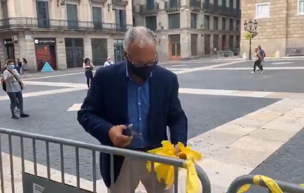 El presidente del PP en el Ayuntamiento de Barcelona, Josep Bou, quitando lazos amarillos de la entrada del consistorio.