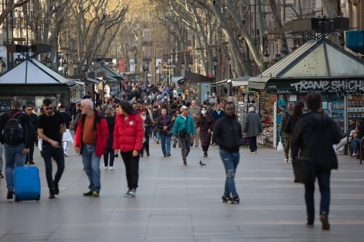 Varias personas caminan por las Ramblas de Barcelona, ciudad en la que, a pesar de haberse reducido, el turismo no ha caído tanto como en Madrid, donde los efectos del coronavirus han sido más letal