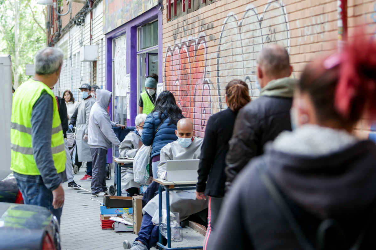 Vecinos realizan una cola para recoger bolsas de la Asociación de Vecinos Parque Aluche durante la pandemia