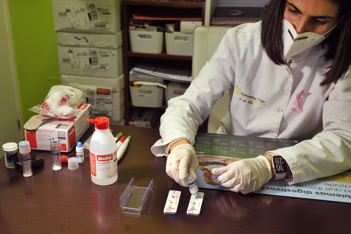 Una farmacéutica de la Farmacia Portal Martínez Soto añade el reactivo a una placa en la que ha introducido la muestra de sangre que ha tomado para realizar un test de cribado del coronavirus en Ba