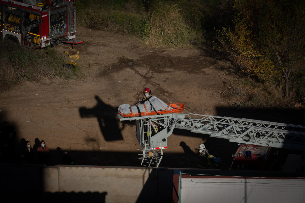 Bomberos retiran el cadáver de una de las personas fallecidas en el incendio de ayer en la nave okupada del barrio de Gorg, en Badalona, Barcelona, Catalunya (España), a 10 de diciembre de 2020.