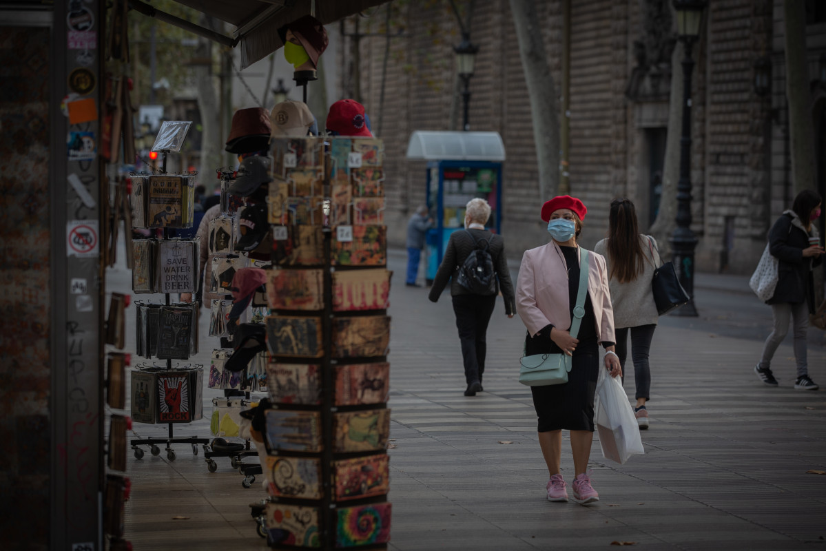 Una mujer frente a una tienda de artículos turísticos en Barcelona, Catalunya (España), a 16 de noviembre de 2020. El turismo internacional se desplomó este verano debido como consecuencia del cor