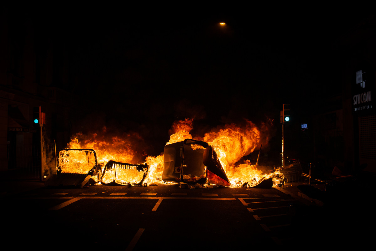Un contenedor incendiado por los manifestantes que apoyan a Pablo Hasel durante los disturbios en Barcelona (España), a 17 de febrero de 2021. El rapero Pablo Hasel ingresó la mañana de ayer martes