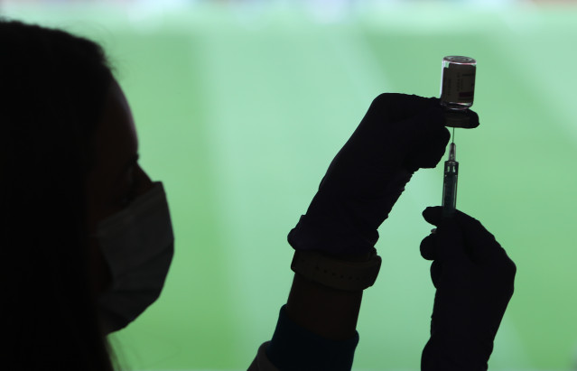 Un profesional sanitaria sostiene una jeringuilla y un vial con la vacuna del Covid-19, en un dispositivo instalado en el Estadio Wanda Metropolitano, en Madrid (España), a 30 de marzo de 2021.