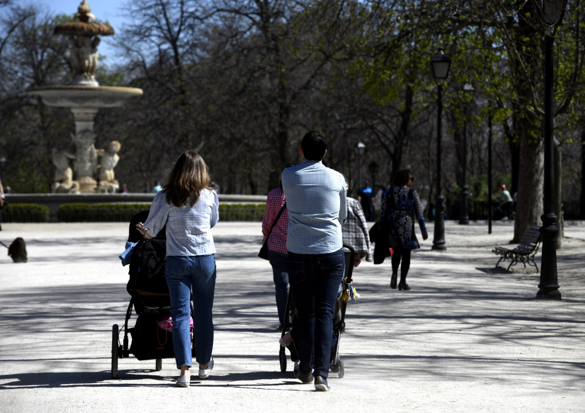 Archivo - Unos padres pasean a sus hijos en sillitas de bebé por el Parque del Retiro.