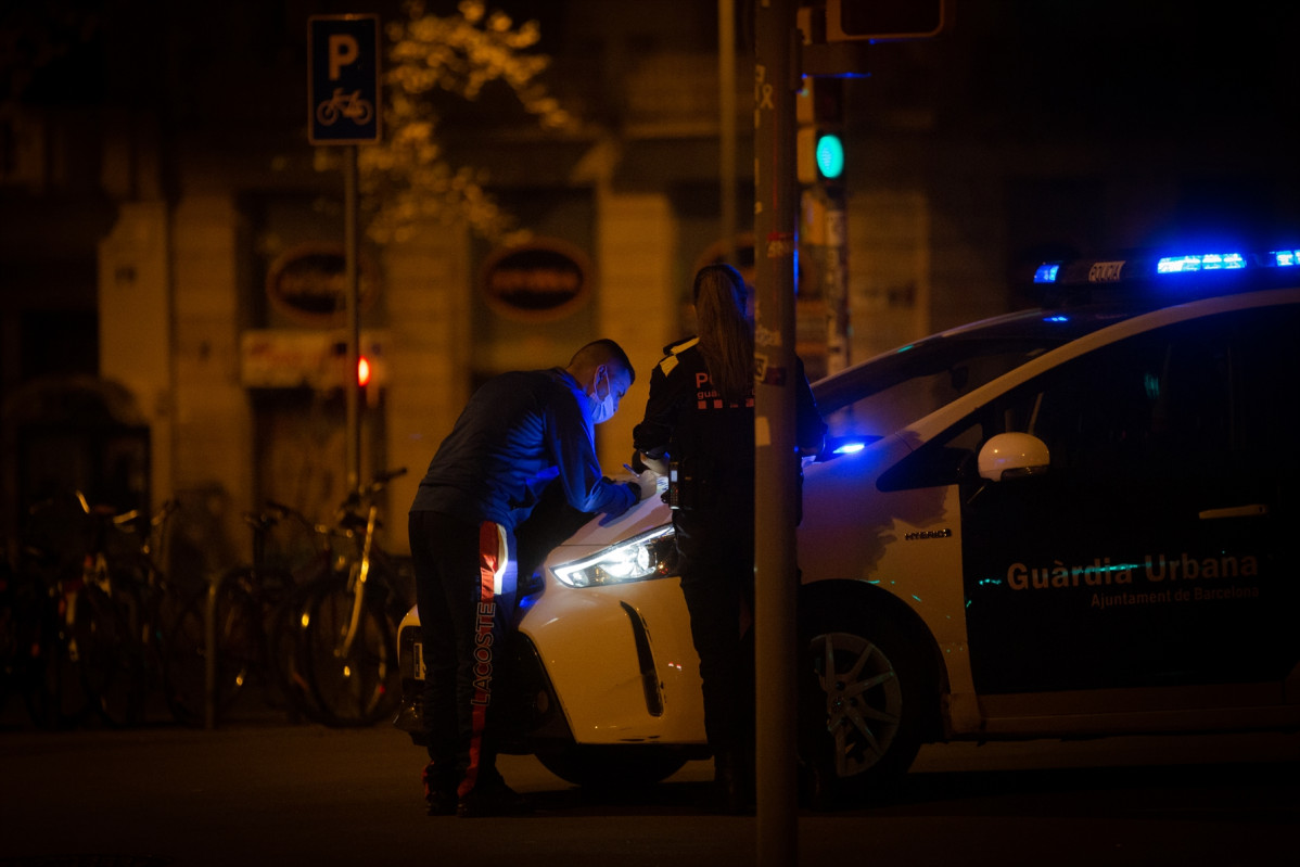 Archivo - Un hombre firma en el capó de un vehículo de la Guardia Urbana una multa por saltarse el toque de queda, en el Arc de Triomf, Barcelona, Catalunya, (España), a 2 de noviembre de 2020.