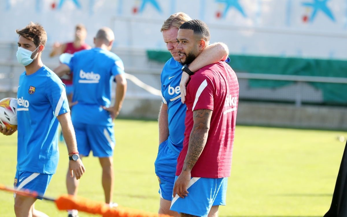 El entrenador del FC Barcelona, Ronald Koeman, abraza a su nuevo jugador Memphis Depay en su primer entrenamiento con el equipo blaugrana, el 20 de julio de 2021