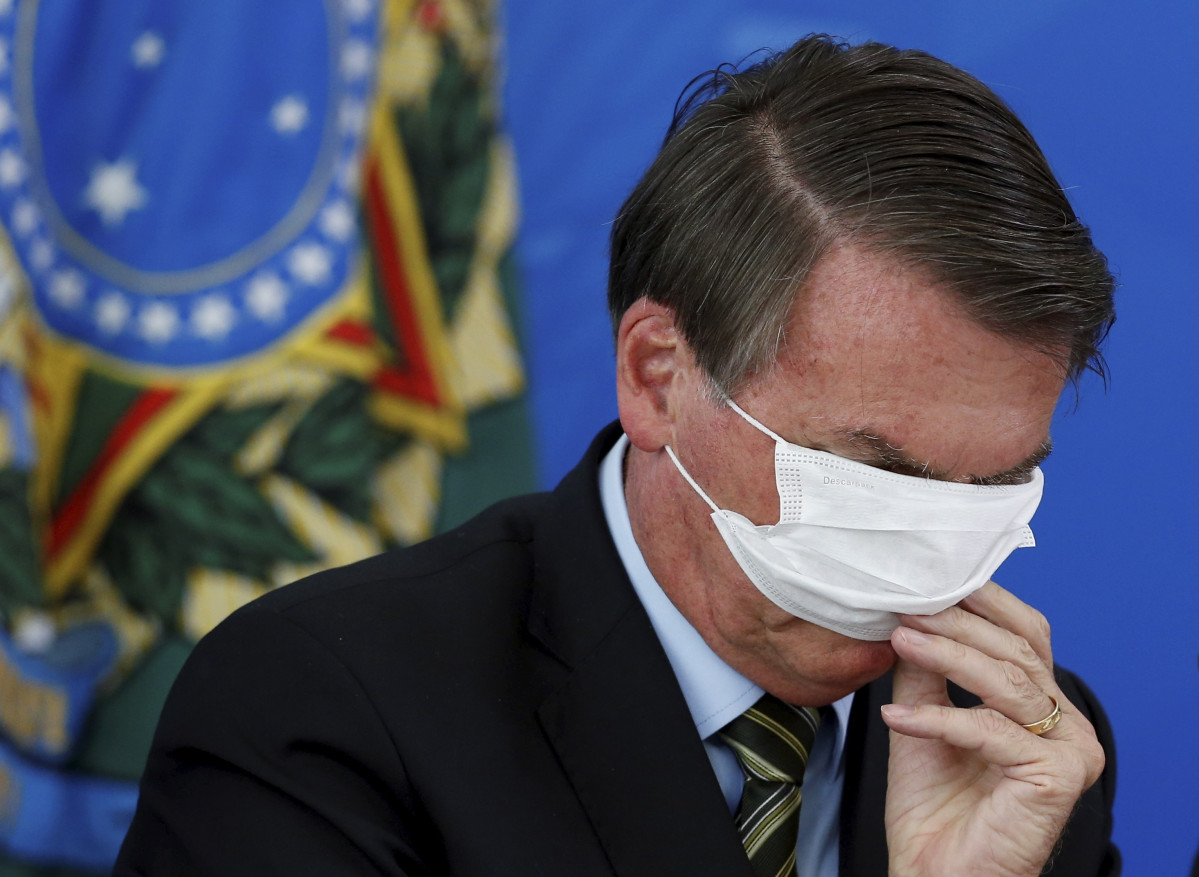 Archivo - Arxivo - El president del Brasil, Jair Bolsonaro, intenta posar-se una mascarilla