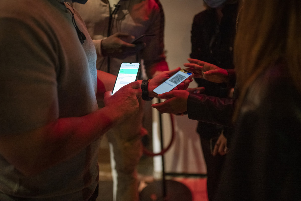 Una persona muestra un código QR para entrar a un local de ocio nocturno la misma noche en que entra en vigor la reapertura en interiores a medianoche, a 8 de octubre de 2021, en Barcelona, Cataluña