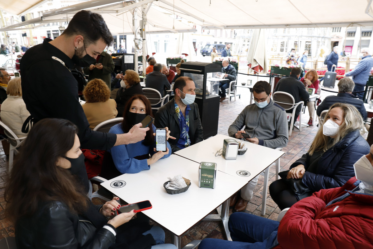 Un camarero pide certificado a los clientes en una mesa en la terraza de un bar durante el primer día de petición de Certificados Covid-19 para la hostelería, a 20 de diciembre de 2021 en Málaga (