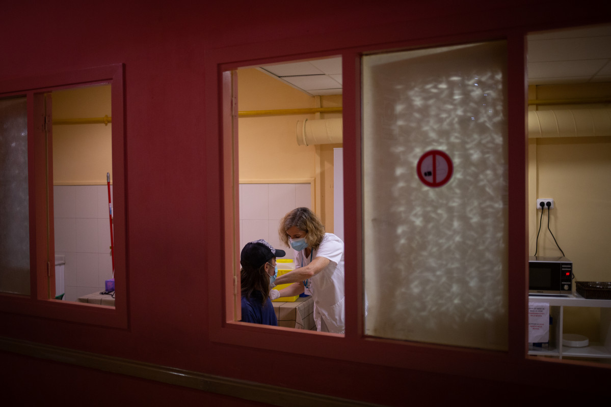 Archivo - Una sanitaria vacuna a una mujer en Barcelona