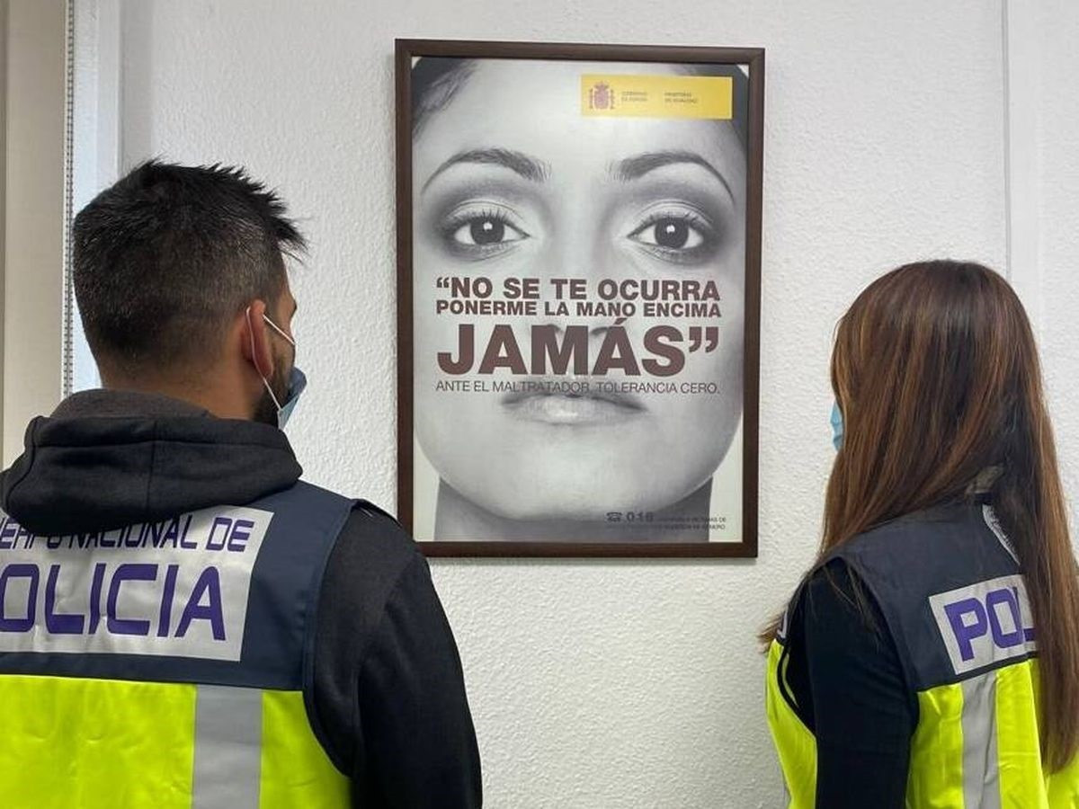 Archivo - Agentes observan un cartel de concienciación contra la violencia de género.