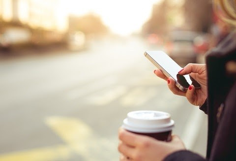 Una persona mira su móvil mientras toma un café