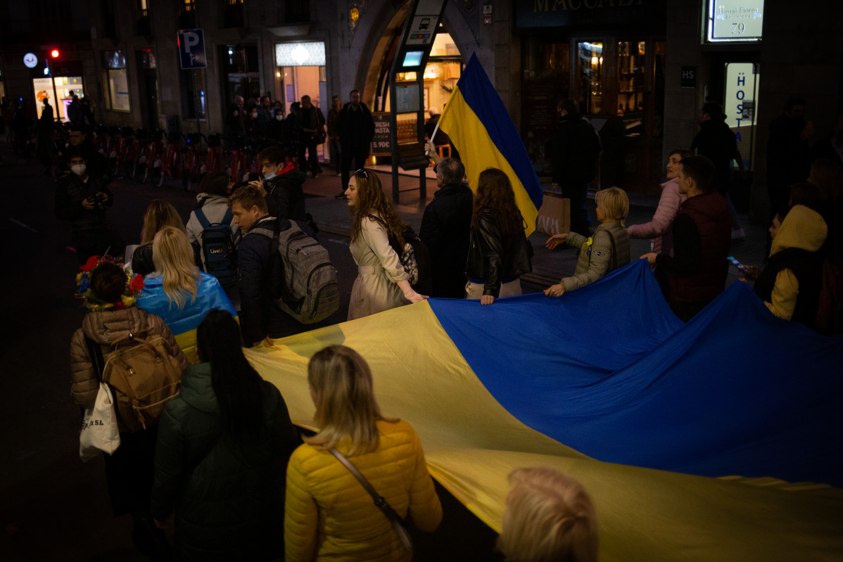 Un grupo de personas sostienen la bandera de Ucrania en una concentración ante la embajada rusa en Barcelona tras los primeros ataques rusos registrados en Ucrania esta pasada madrugada, a 24 de febr