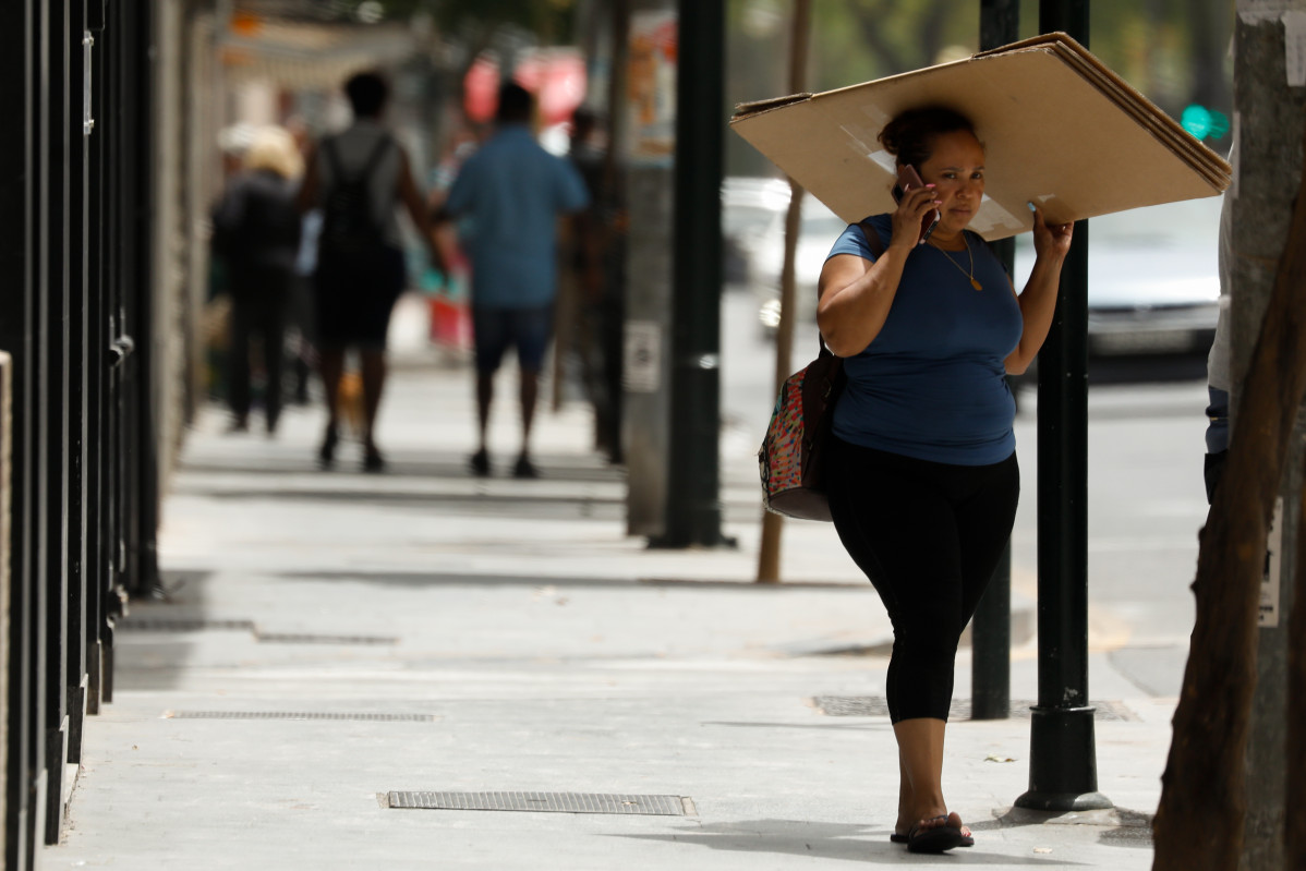 Archivo - Una mujer se protege del sol con una caja de cartón durante un día de alerta roja por altas temperaturas, a 12 de julio de 2021, en la ciudad de Murcia