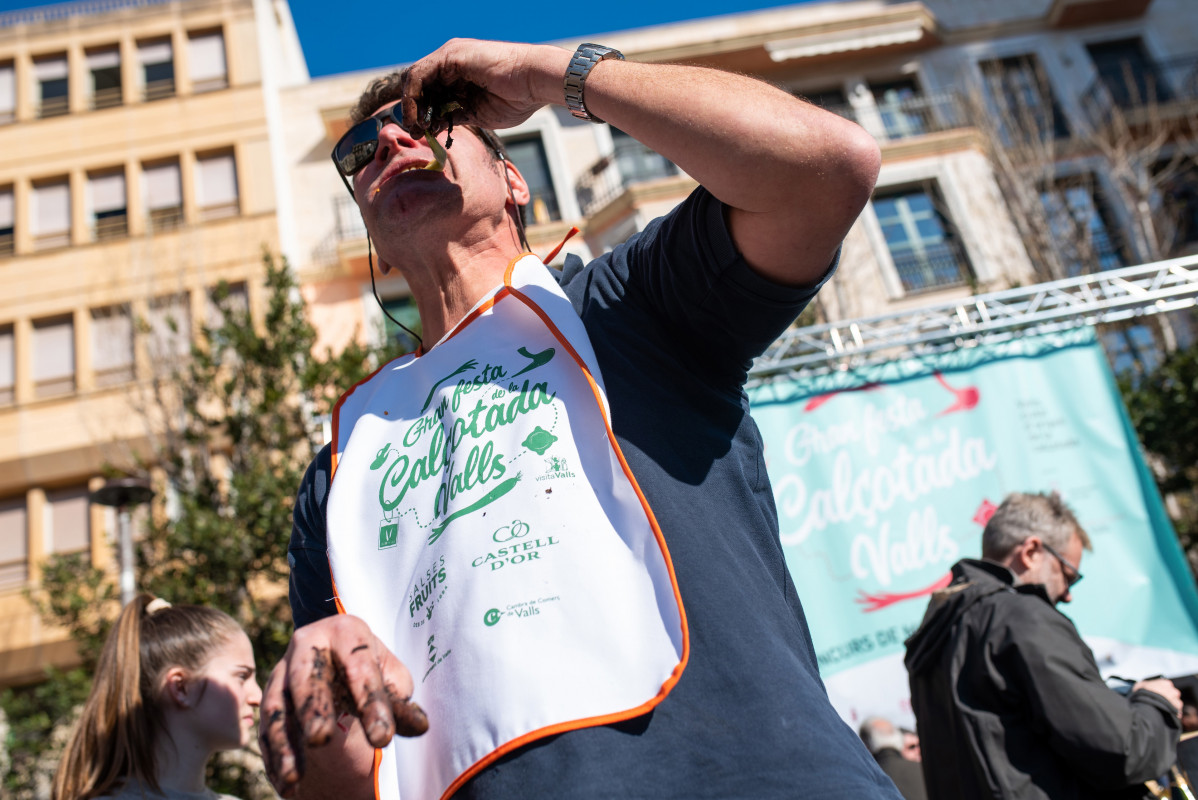 Adrià Wegrzyn se come un calçot durante la fiesta de la Calçotada, a 29 de enero de 2023, en Tarragona, Catalunya