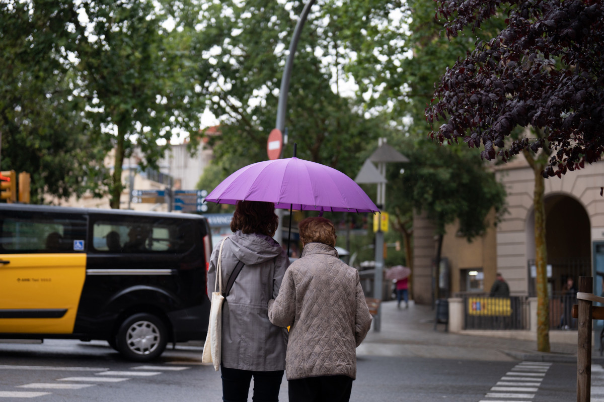 Varias personas con paraguas pasean por una de las calles de la ciudad, a 12 de mayo de 2023, en Barcelona