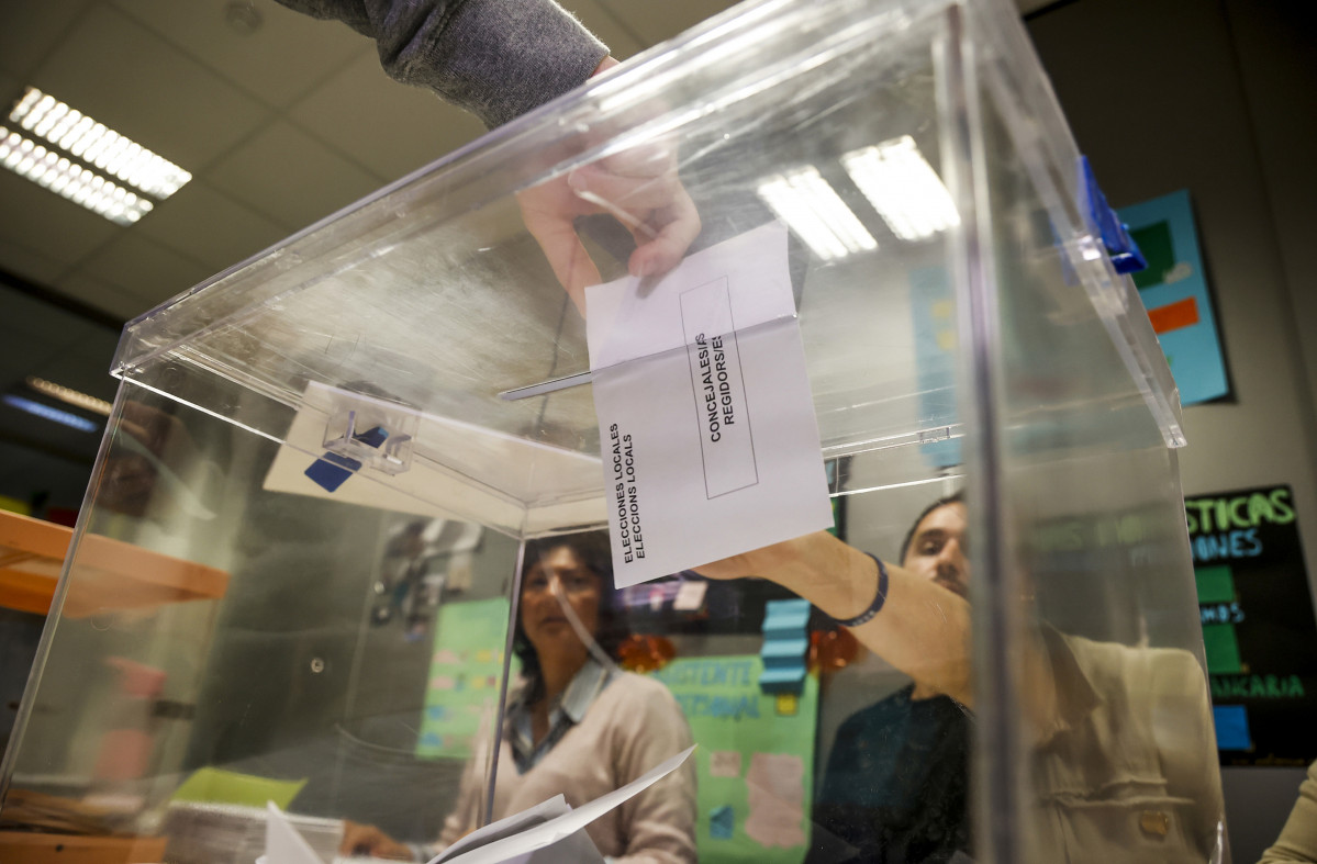 Una persona deposita su voto en una urna.
