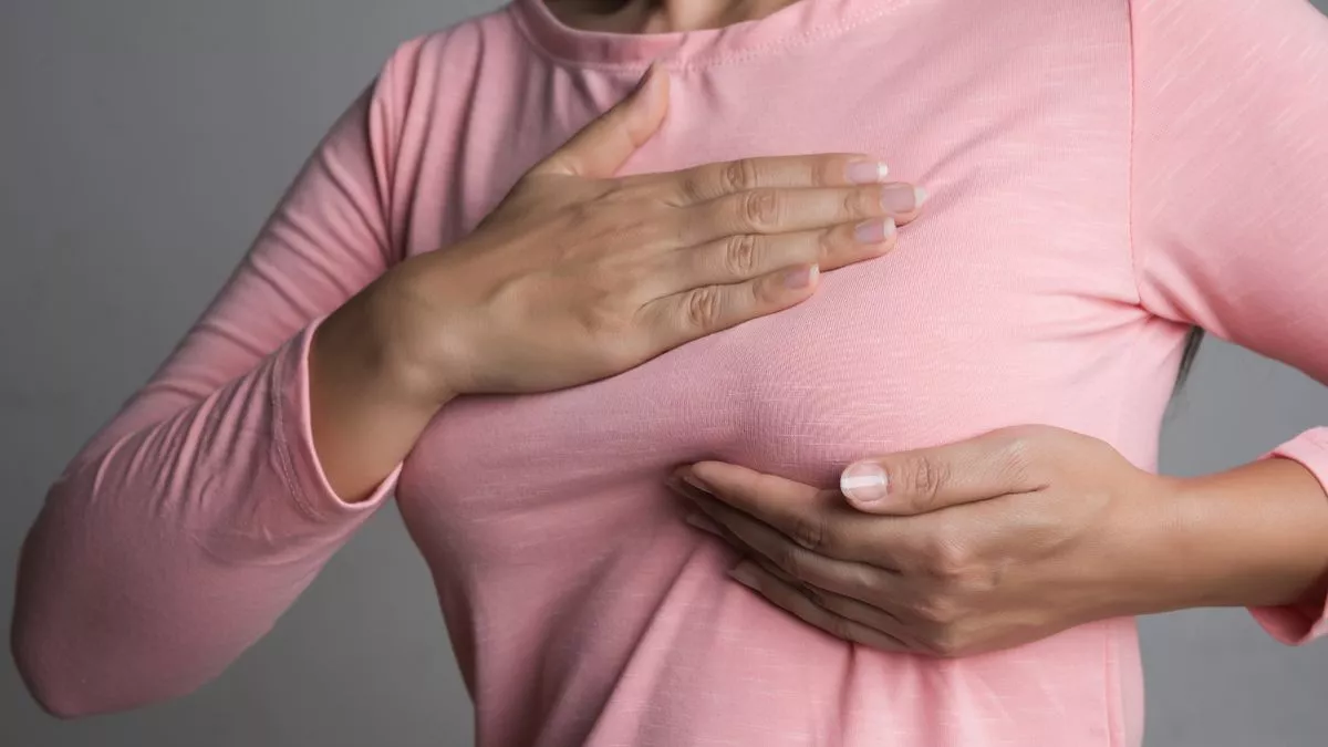 0 Woman hand checking lumps on her breast for signs of breast cancer on gray background Healthcare co