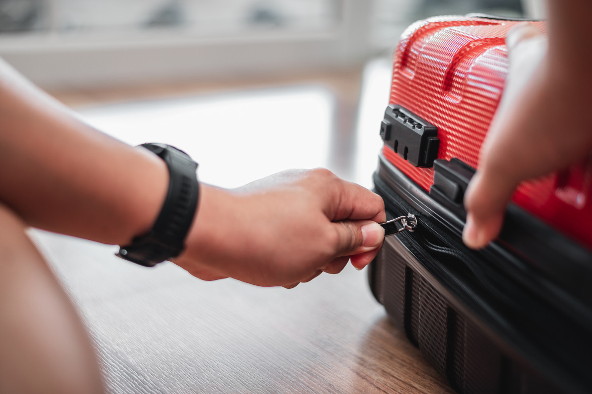 Primer plano hombre viajero ha terminado empacar bloqueando hombre preparando ropa maletas concepto vacaciones vacaciones viaje