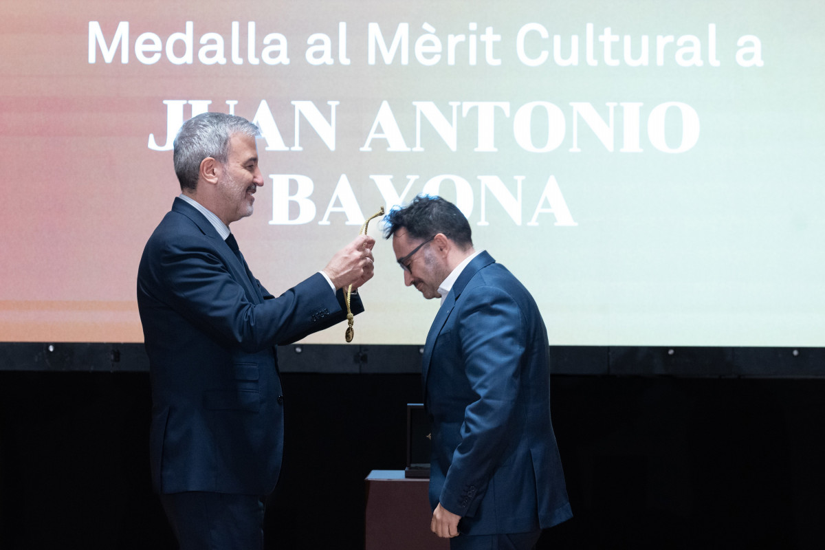 El alcalde de Barcelona, Jaume Collboni (i), entrega la Medalla al Mèrit Cultural al cineasta Juan Antonio Bayona (d), en el Ayuntamiento de Barcelona, a 10 de diciembre de 2024, en Barcelona, Catalu