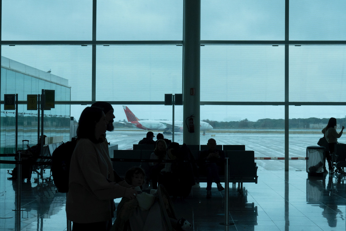 Archivo - Varias personas esperan sentadas frente a un avión aparcado en la pista del aeropuerto de El Prat, a 19 de enero de 2023, en el Prat de Llobregat, Barcelona, Catalunya