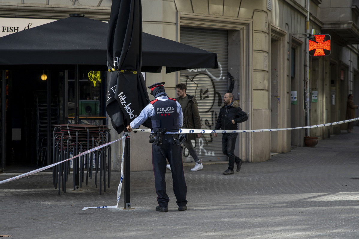 Archivo - Un agente acordona la zona donde se encontró un cadáver en un contenedor del centro de Barcelona.