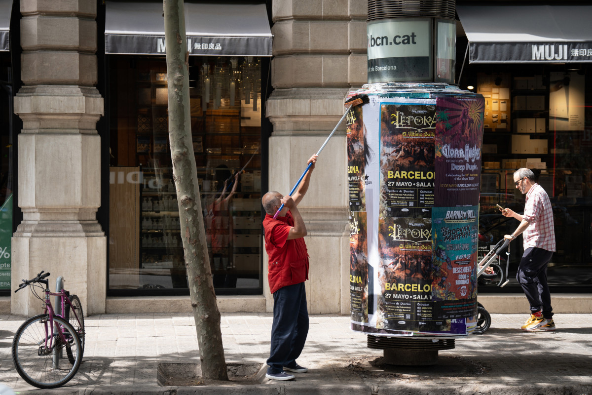 Archivo - Un operario pega carteles en Barcelona