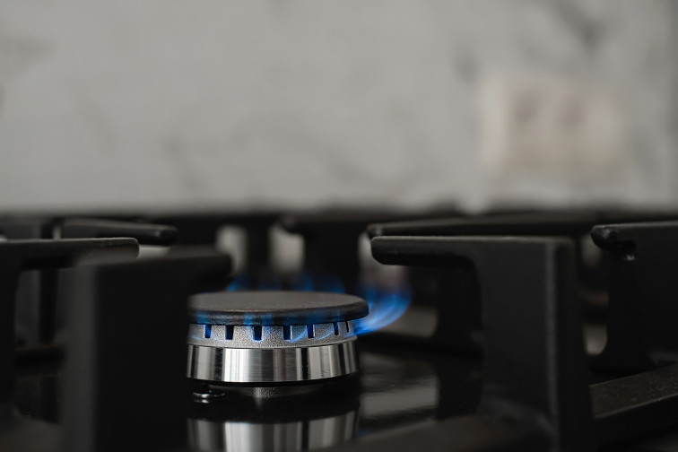 Modern kitchen stove natural gas burns with blue flame household gas consumption close up selective focus